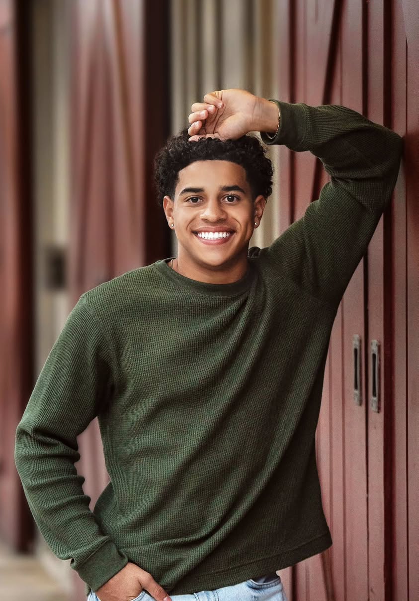 A senior portrait against weathered red barn doors